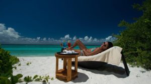 En kvinna solar och njuter på stranden på en resa till Maldiverna